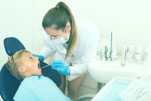 Odontóloga mirando boca a niño 